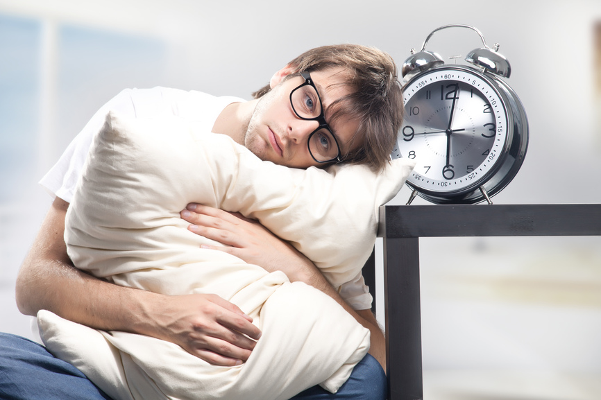 Sad man holding pillow and the clock